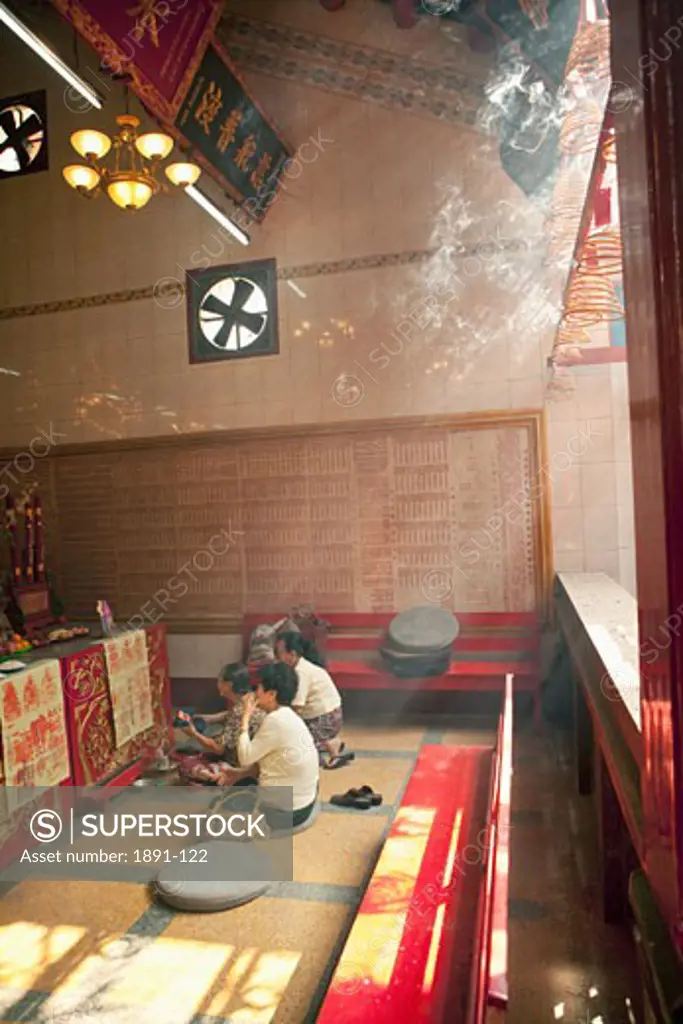 Three people praying in a Chinese temple, Myanmar