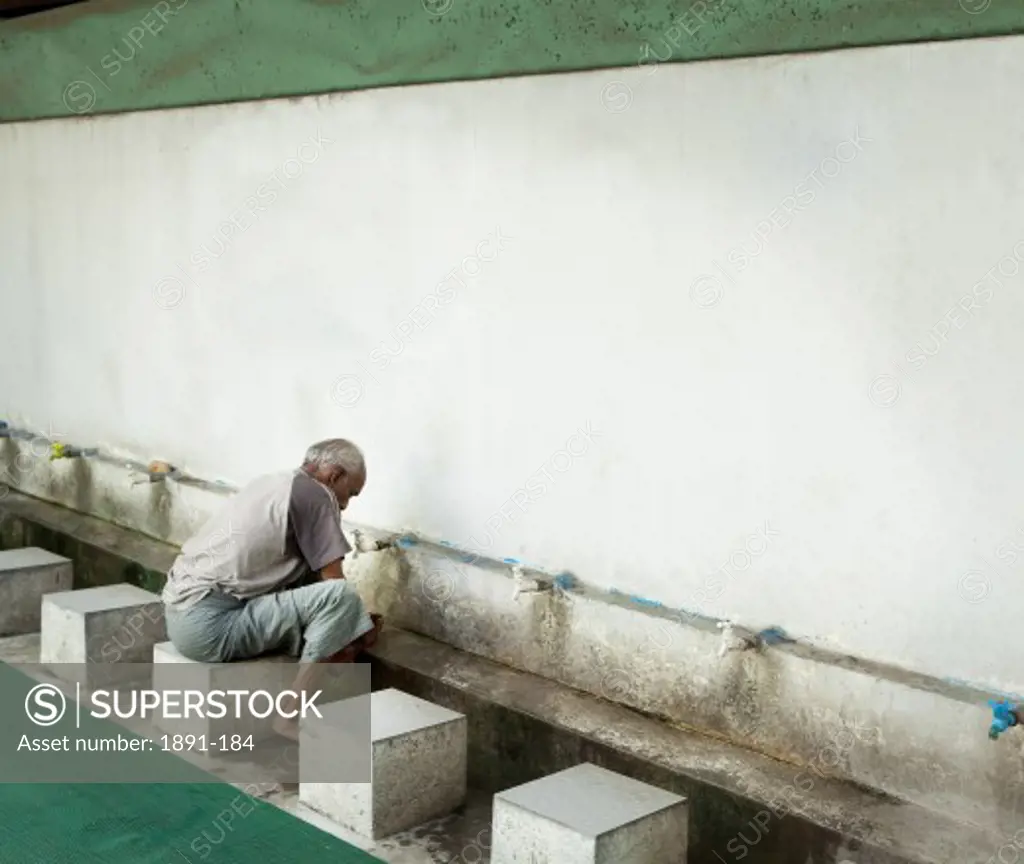 Man washing his feet at the entrance of a mosque, Myanmar