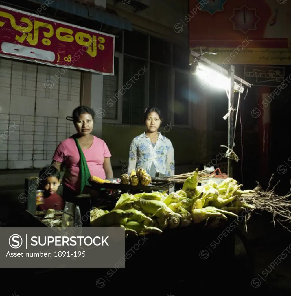 Woman with her children standing at a vegetable stall, Myanmar