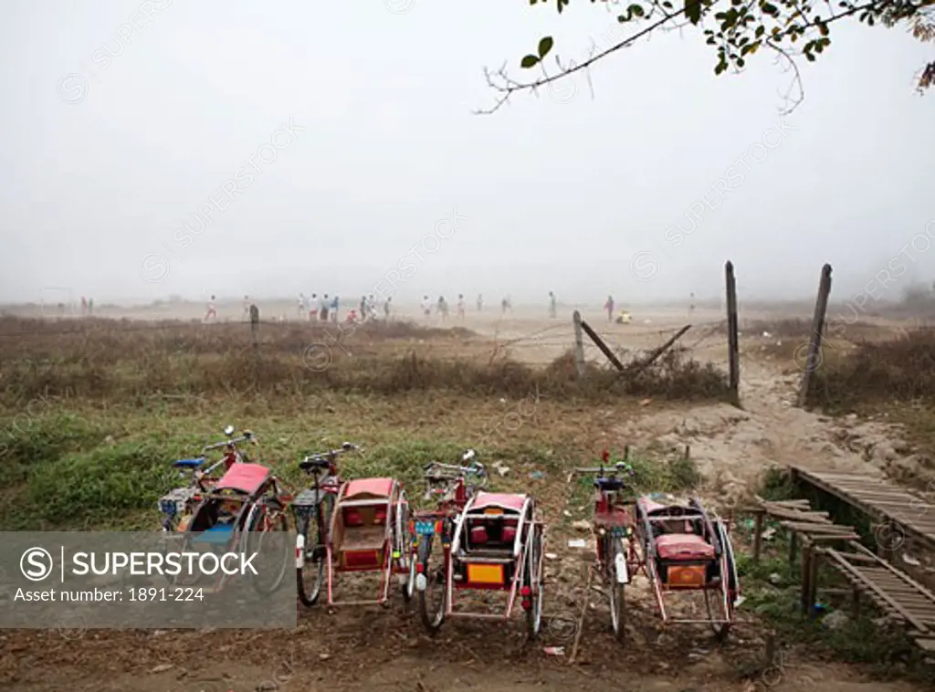 Pedicabs with a soccer game held in the background, Myanmar