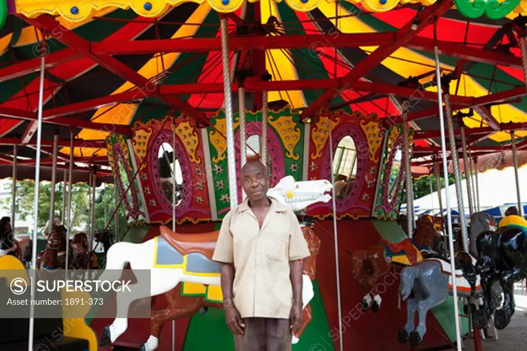 Male attendant standing in front of a carousel, Jamaica