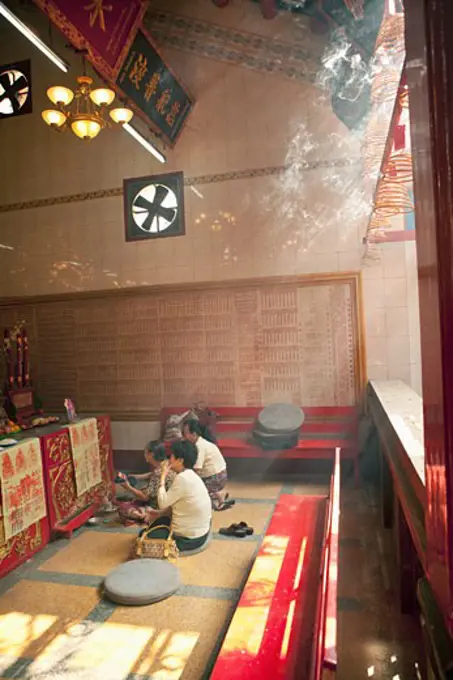 Three people praying in a Chinese temple, Myanmar