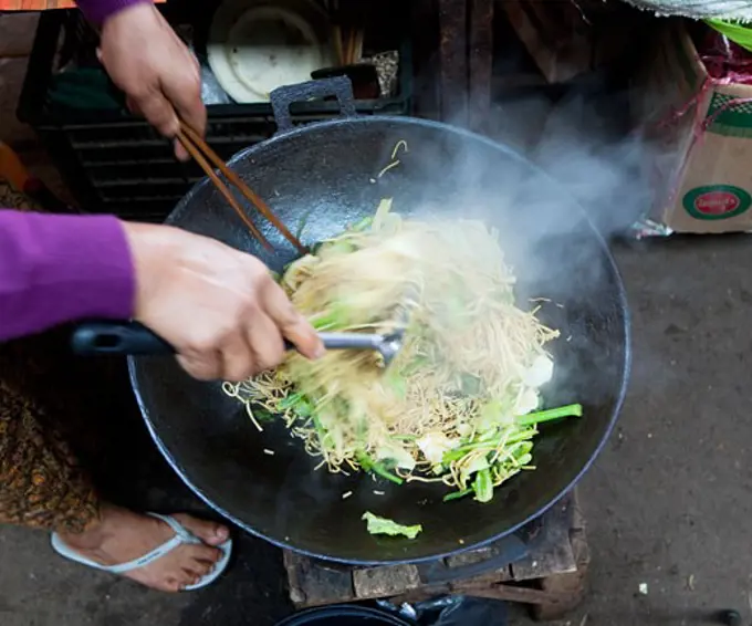 Woman cooking noodles in a street market, Myanmar