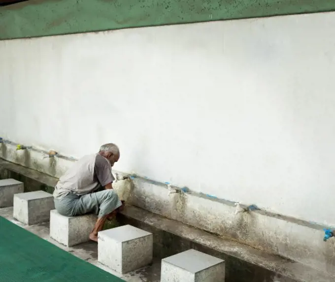 Man washing his feet at the entrance of a mosque, Myanmar