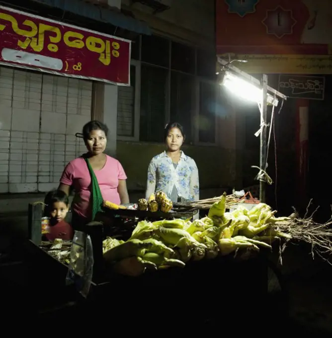 Woman with her children standing at a vegetable stall, Myanmar