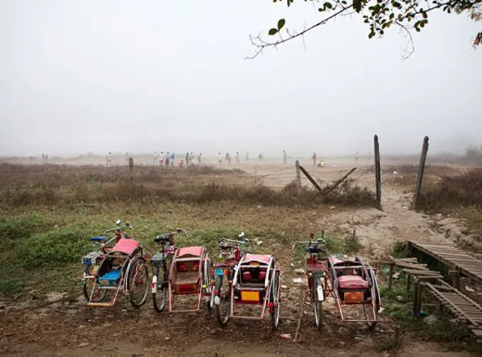 Pedicabs with a soccer game held in the background, Myanmar