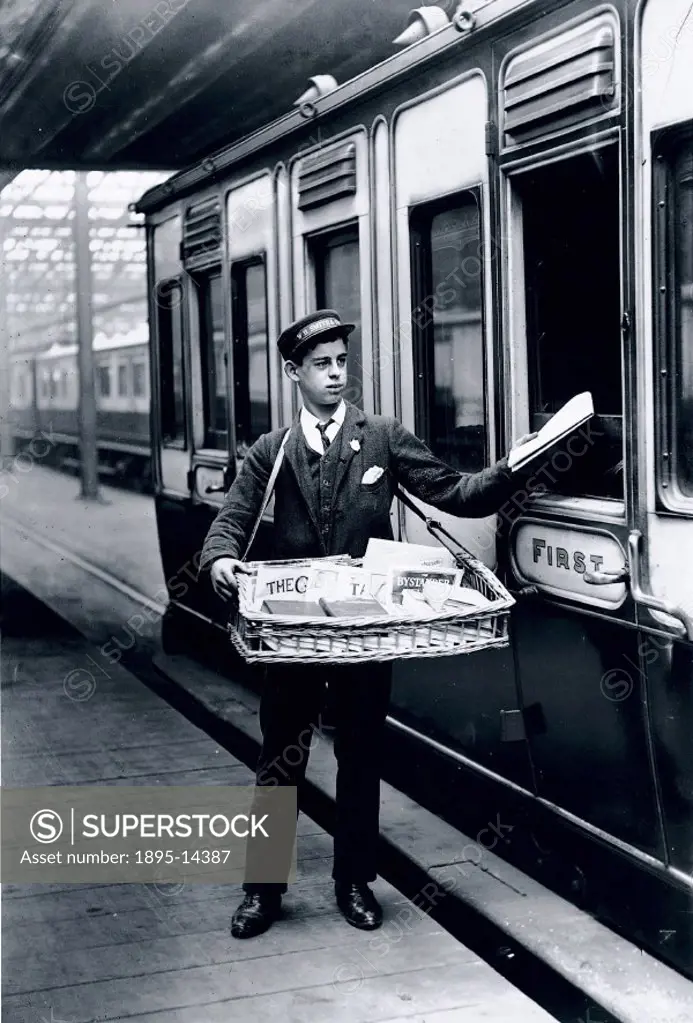 Official London & North Western Railway photograph showing a boy selling newspapers to passengers in a first class carriage of a train at Holyhead Sta...