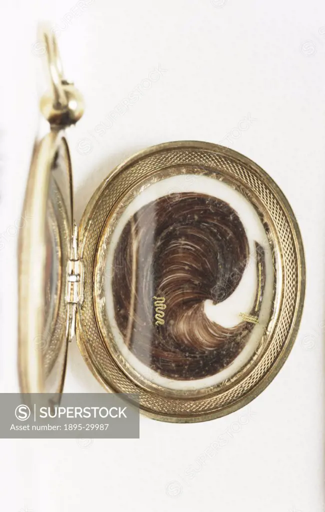 A lock of hair bound with gold thread and encased in a gold locket, created by an unknown maker in about 1850.  The exterior of the gold locket has an...