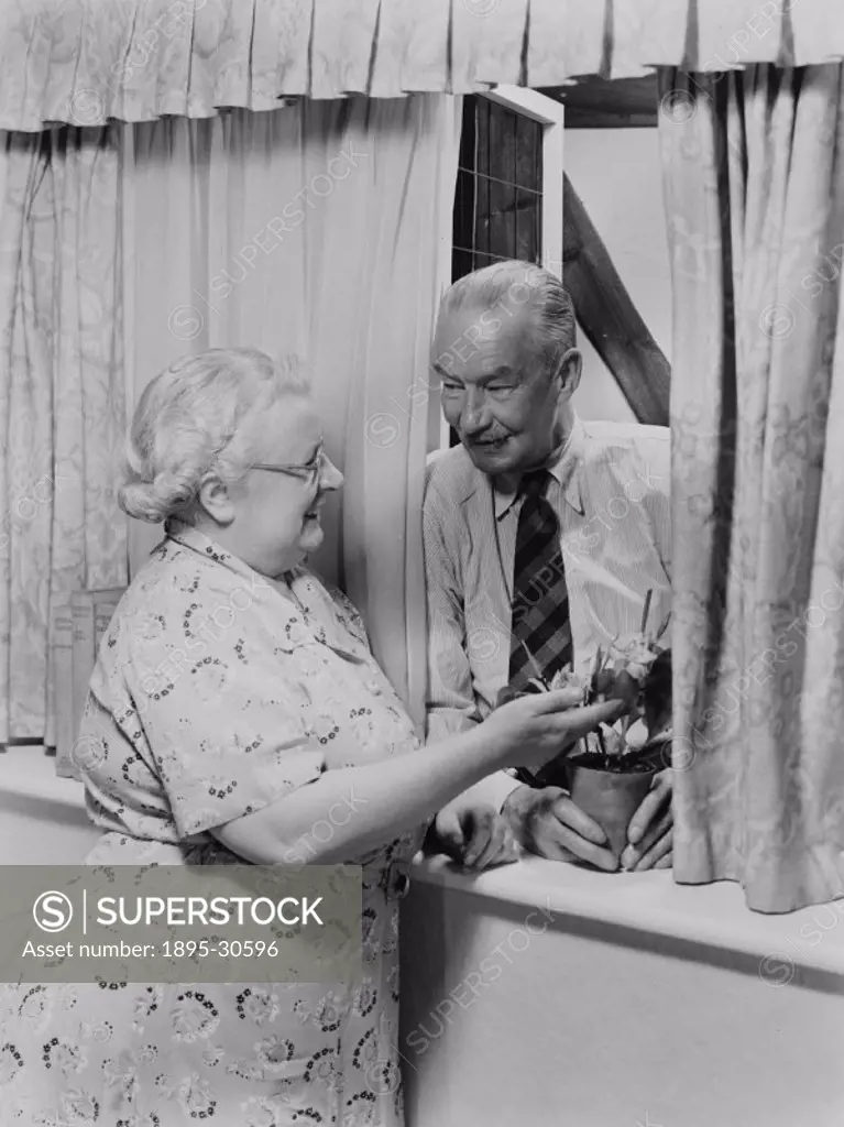 A photograph of an elderly couple talking at a window, taken by Photographic Advertising in about 1950.  The image suggests contentment in retirement....