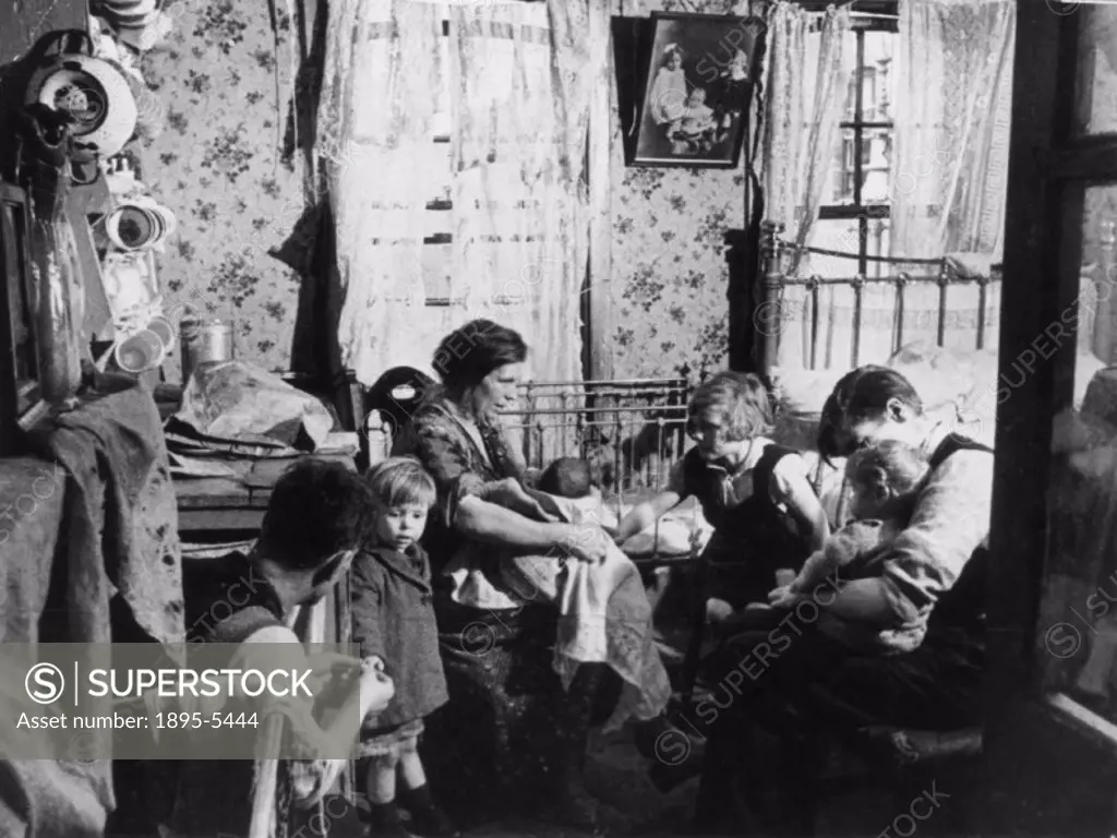 Photograph of ´A slum home in Old Gravel Lane, Wapping. Two rooms for these three grown-ups and four children. Yet they carry on the struggle to bring...