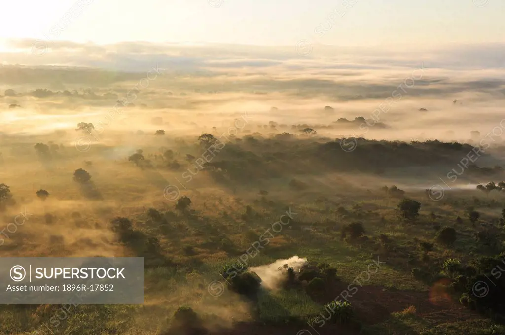 Dawn over grassland dotted with fields, encroaching mist, Central Mozambique