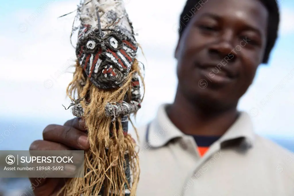 Man Holding up an African Voodoo Doll  Cape Town, Western Cape Province, South Africa