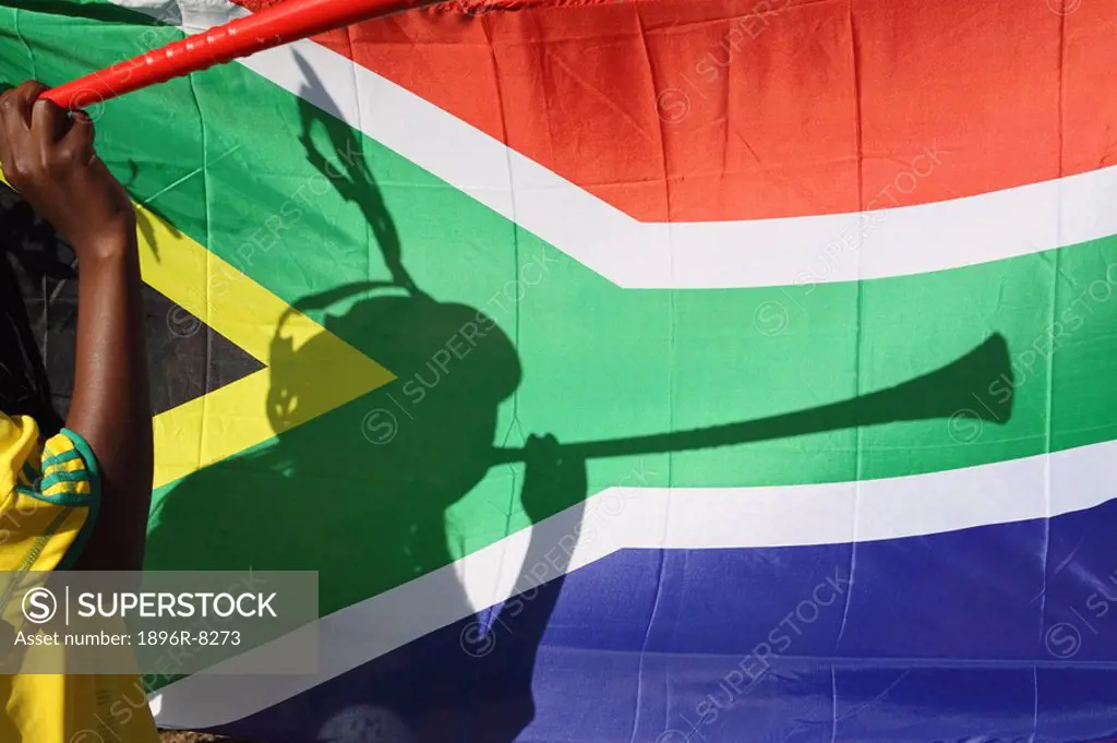 Shadow of soccer supporter blowing vuvuzela, South African flag in backgrund, Johannesburg, South Africa