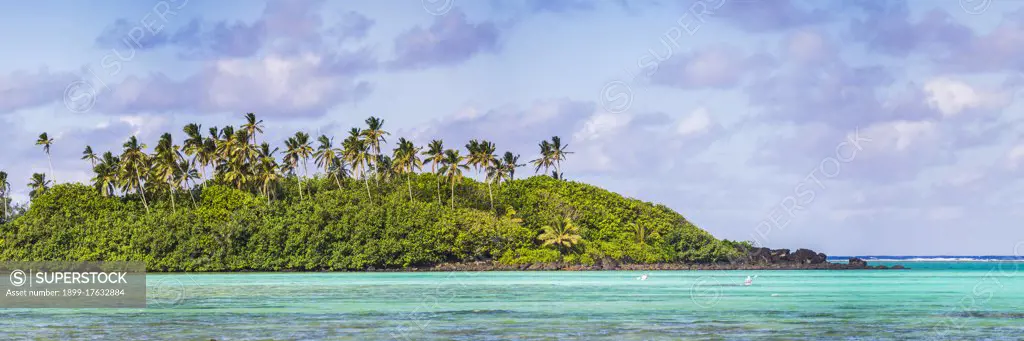 Tropical Island covered in palm trees above the perfect blue water of the Pacific Ocean at Muri Lagoon, Rarotonga, Cook Islands