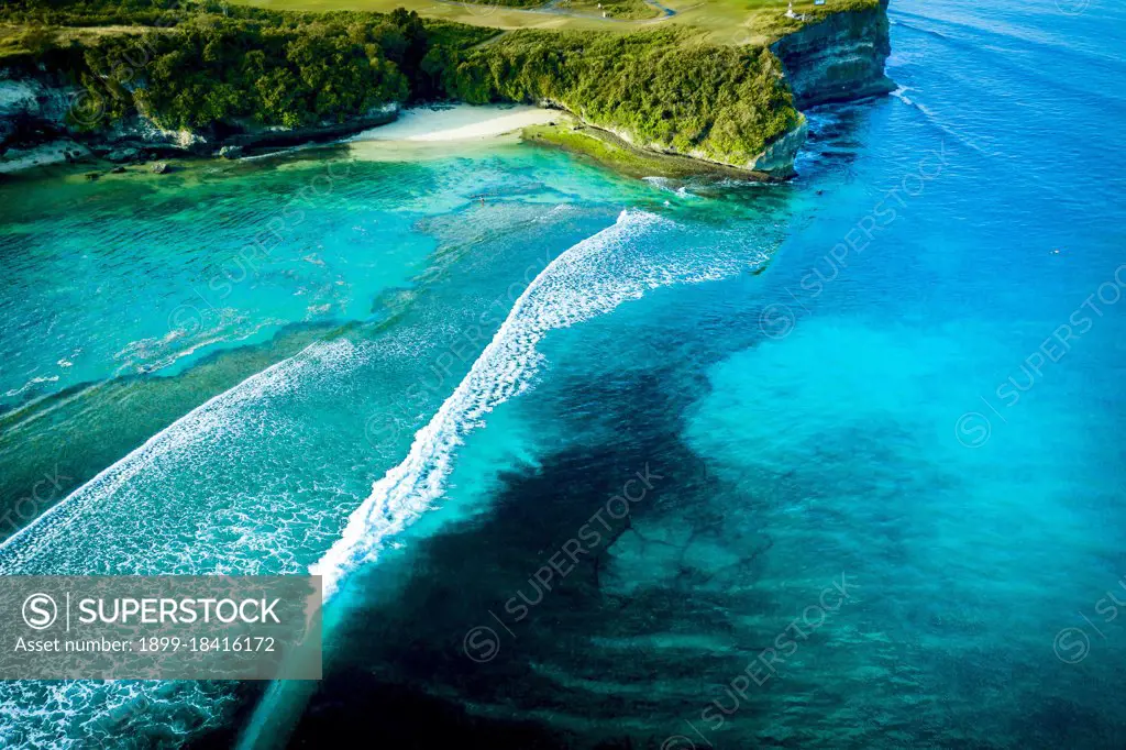 Aerial view of a tropical cove with large waves breaking