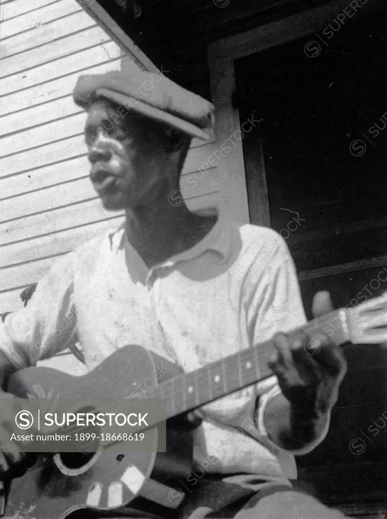 Bill Tatnall, half-length portrait, seated, facing left, playing guitar, Frederica, Georgia circa June 1935.