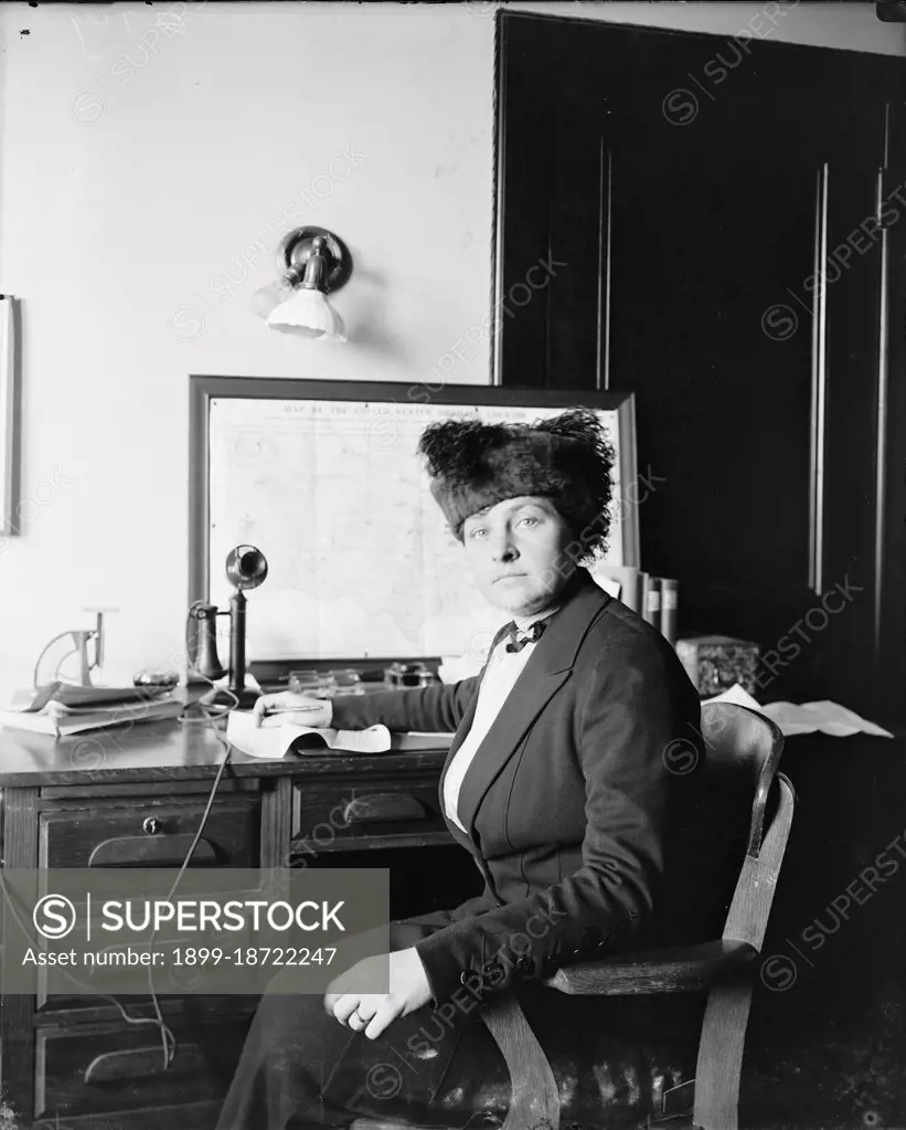 Woman sitting at desk with old telephone circa 1910-1920. 