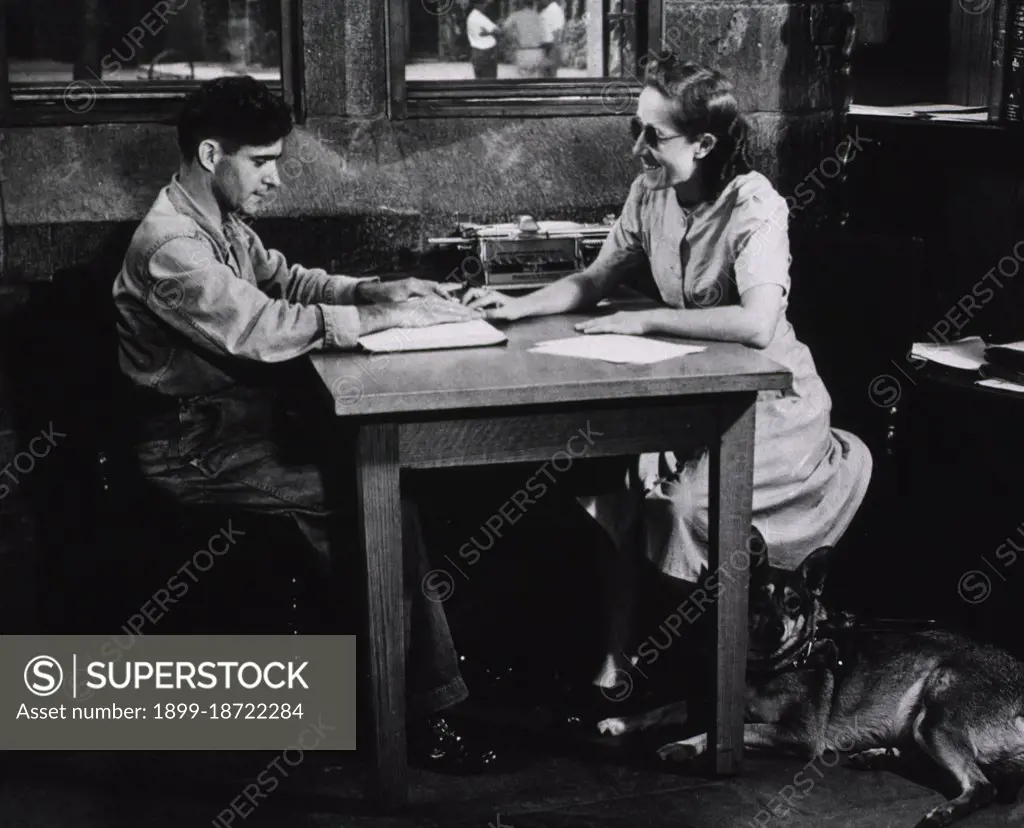 A blind woman teaching a blind man to read Braille circa mid-1900s.