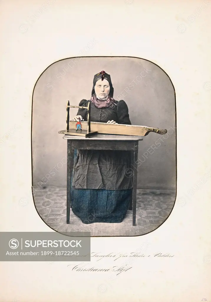 A woman sitting by the table With a langleik in front of her, Slidre i Valdres, circa 1857-1870.