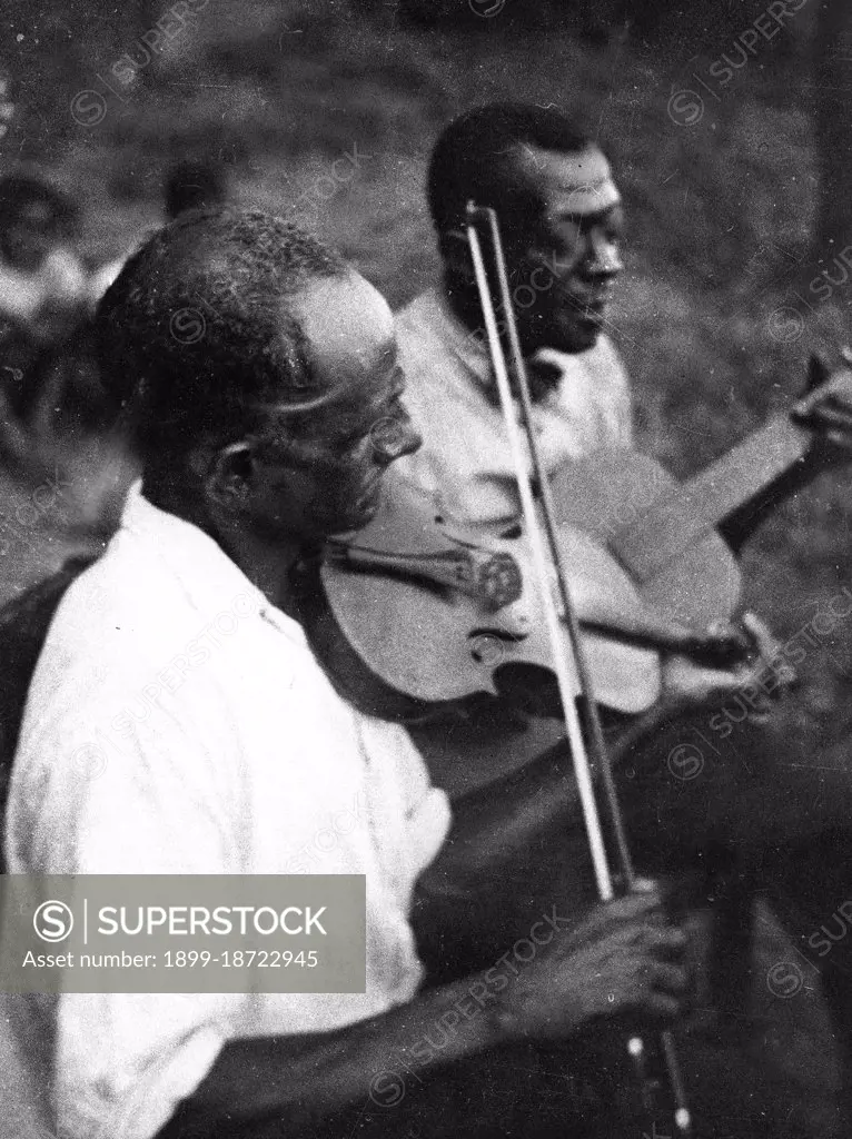 Stavin' Chain playing guitar and singing the ballad 'Batson' accompanied by a musician playing violin, Lafayette, La. circa June 1934.