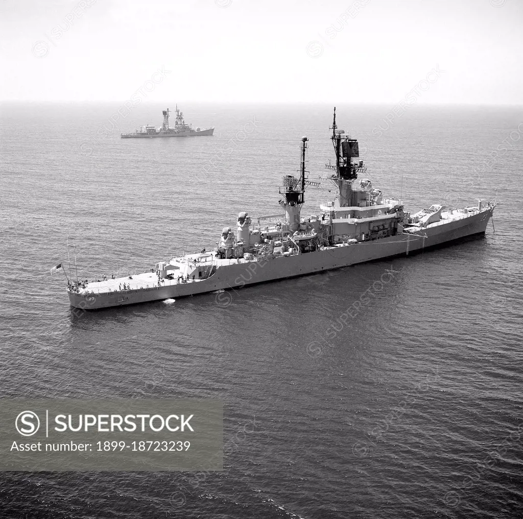 1976 - An aerial starboard quarter view of the guided missile cruiser USS HALSEY (CG 23) anchored off the coast of Southern California.  The guided missile destroyer USS DECATUR (DDG 31) is visible in the background. 