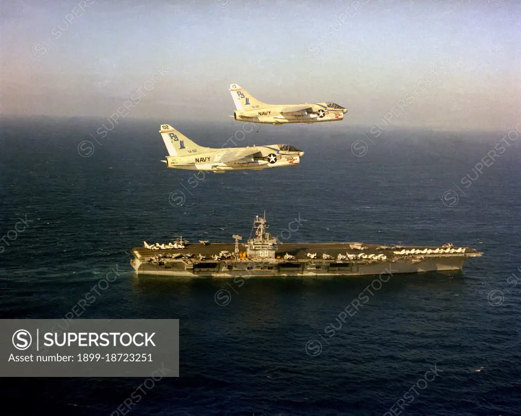 1979 - An aerial starboard view of the nuclear-powered aircraft carrier USS NIMITZ (CVN-68) underway with two A-7E Corsair II aircraft from Light Attack Squadron 82 (VA-82) in flight above the ship. 