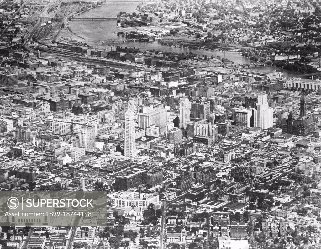 Aerial view of downtown Minneapolis, MN, with the Mississippi River in the background and Minneapolis Auditorium in the foreground. Minneapolis, MN, 1954. 