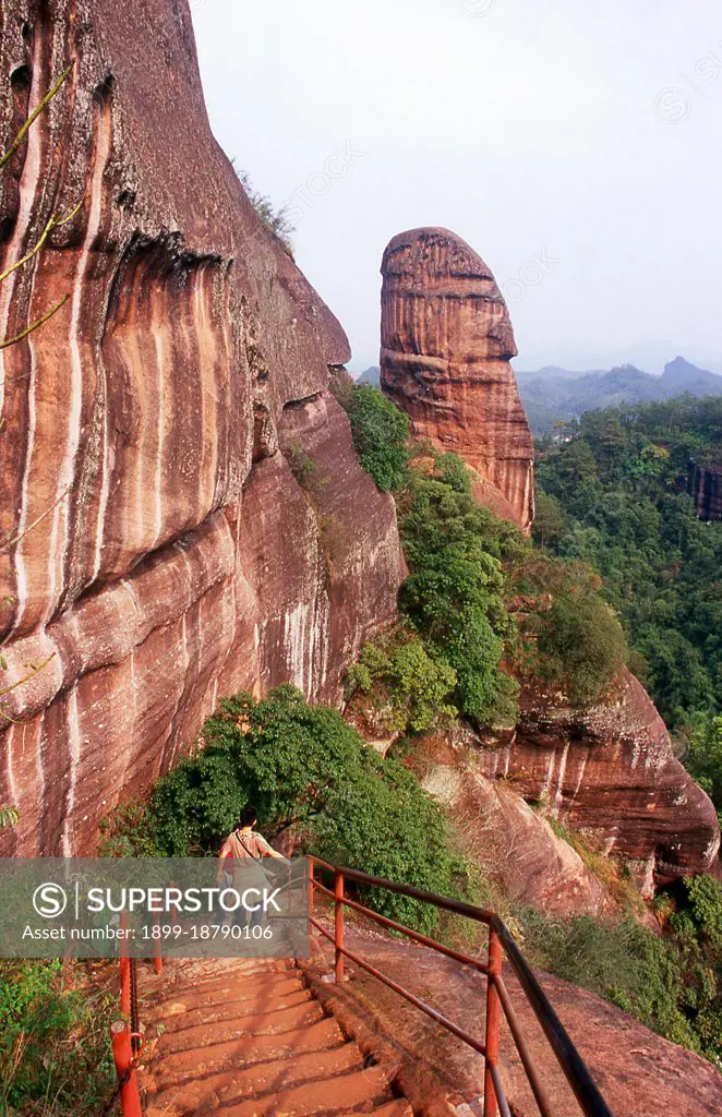 Danxia Mountain meaning Red Rosy Clouds Mountain, is a famous scenic area near Shaoguan city in the northern part of Guangdong Province. The area is formed from a reddish sandstone which has been eroded over time into a series of mountains surrounded by curvaceous cliffs and many unusual rock formations (Danxia Landform). There are a number of temples located on the mountains and many scenic walks. There is also a river winding through the mountains on which boat trips can be taken to enjoy the scenery. Particularly noted are two formations: a stone pillar called the Yangyuan (male/father stone) that bears a resemblance to a phallus and the Yinyuan hole, which somewhat resembles labia.