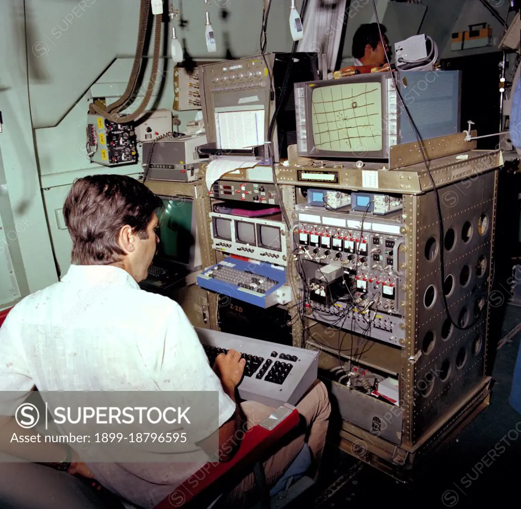 Astronomer at C-141 KAO workstation (rack) during flight of Harper Flange package ca. 1979. 