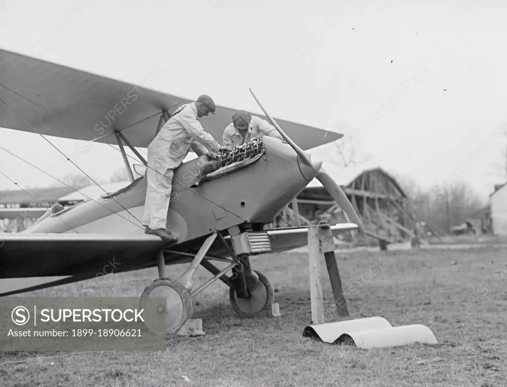 Men examining airplane engine ca. between 1909 and 1923.