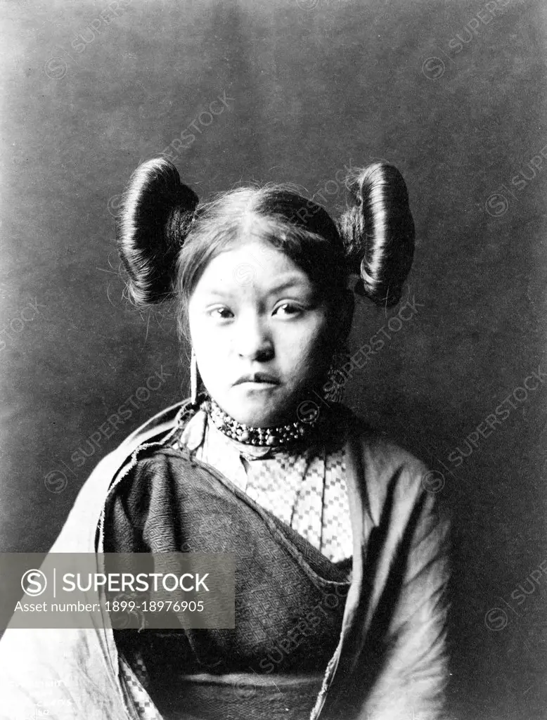 Gobuguoy, Walpi girl, hair tied in swirls on sides of head, cotton shawl around shoulders ca. 1900. 