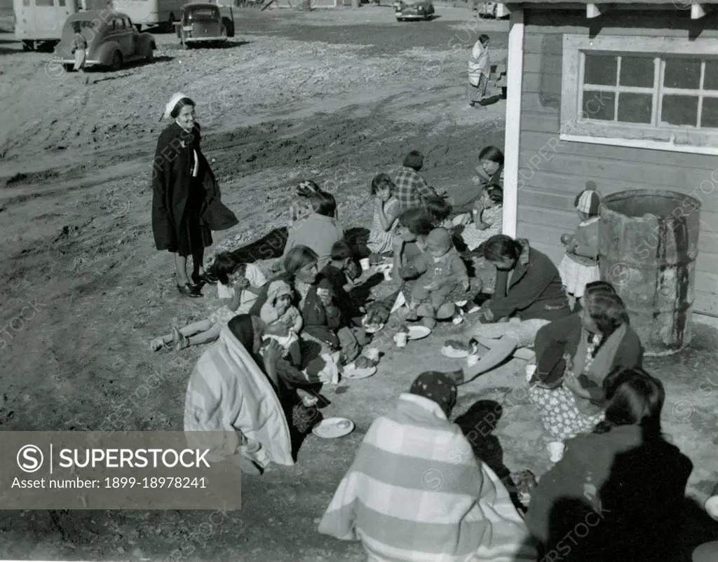 Native Americans Sit on Ground Eating While Woman Looks On ca 1938. 