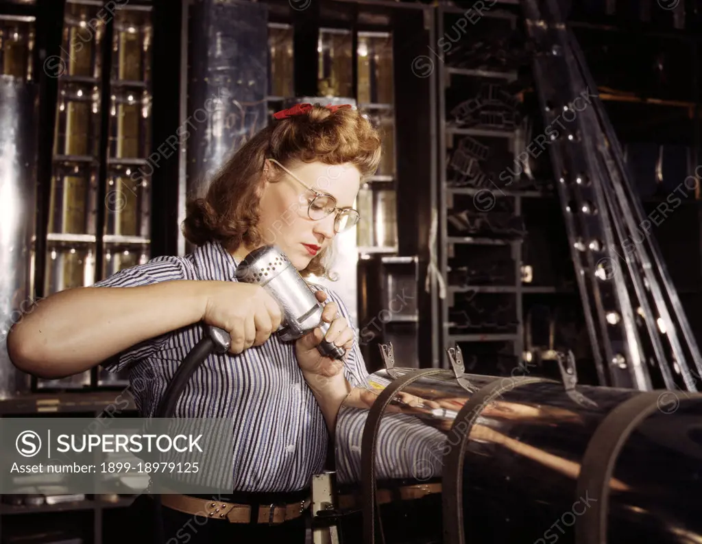 Operating a hand drill at North American Aviation, Inc., a woman is working in the control surface department assembling a section of the leading edge for the horizontal stabilizer of a plane, Inglewood, Calif. - October 1942. 