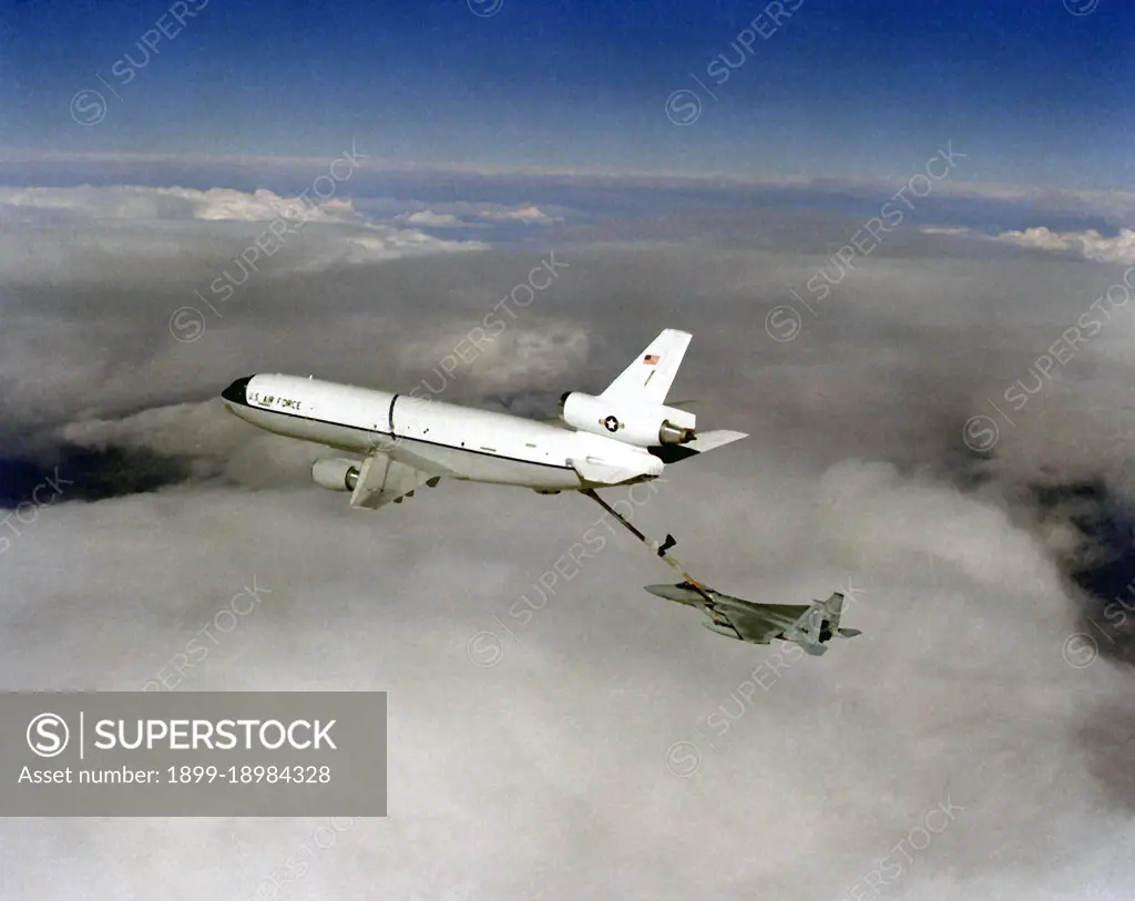 1982 - Air-to-air left side view of a KC-10A Extender aircraft refueling an F-15A Eagle aircraft above the clouds.. 