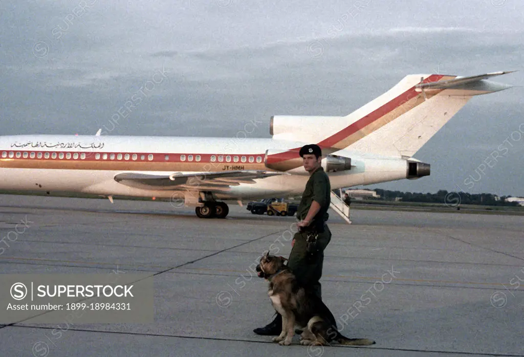 1980 - A security policeman and sentry dog watch as a Jordanian airliner departs with King and Queen Hussein Bin-Talal aboard.. 