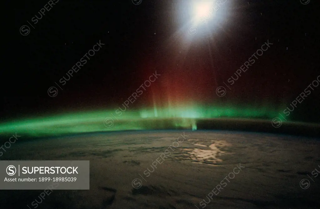 1991 - Moonlight saturates the high speed film used for auroral photography. Moon glint is visible in the open ocean and the cloud patterns are well illuminated. This frame was taken with a handheld 35mm camera from inside the Space Shuttle Discovery's crew cabin.. 