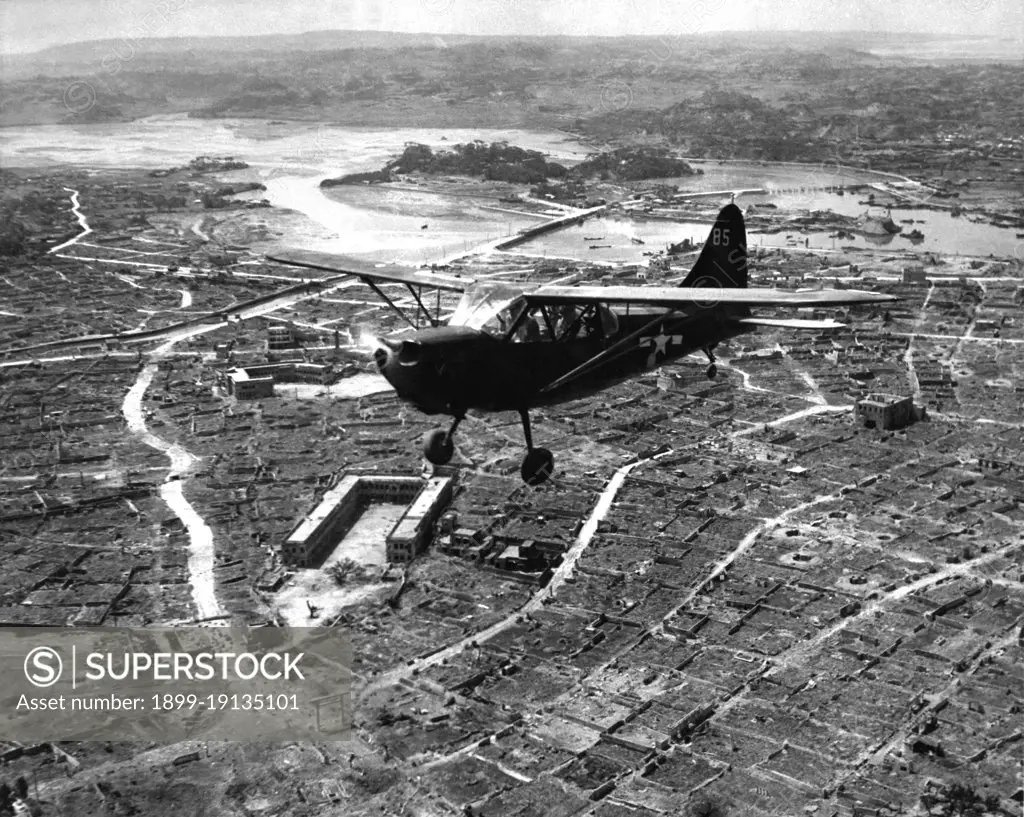 Japan/USA: A U.S. Marine Corps Stinson Sentinel flies over the razed city of Naha, capital of Okinawa. Battle of Okinawa, May 1945