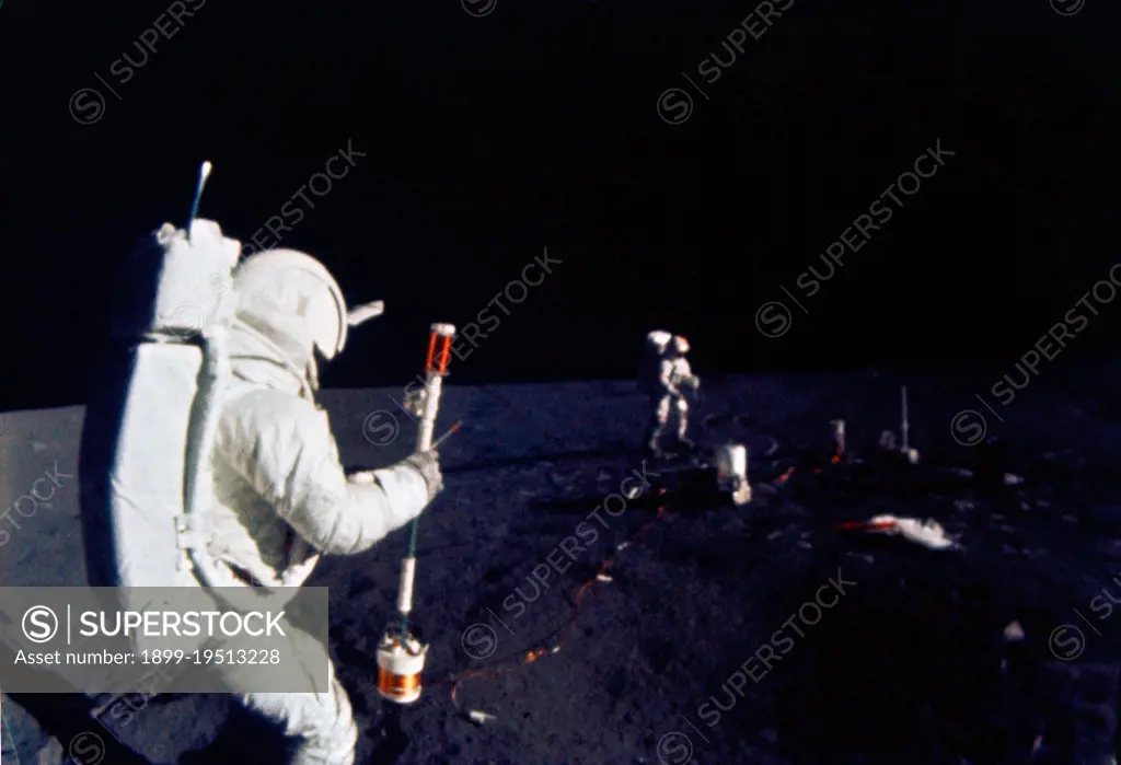 (5 Feb. 1971) --- Astronaut Edgar D. Mitchell, lunar module pilot, operates the Active Seismic Experiment's (ASE) thumper during the first Apollo 14 extravehicular activity (EVA) on the moon. Astronaut Alan B. Shepard Jr., commander, walks near deployed components of the Apollo Lunar Surface Experiments Package (ALSEP) in the background.