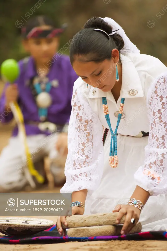 Navajo Indian women demonstrate grinding corn with a mano and metate, Gallup Inter-Tribal Indian Ceremonial, Gallup, New Mexico 