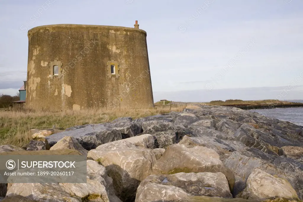 Martello tower defended from erosion by rock armour at East Lane, Bawdsey, Suffolk, England