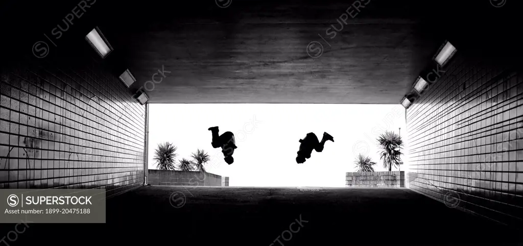 Two parkour athletes perform a backflip.  