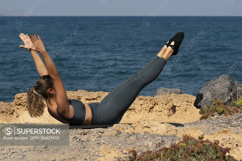 Malia, Crete, Greece, Pilates exercises on the beach in Crete. Double leg  stretch position. - SuperStock