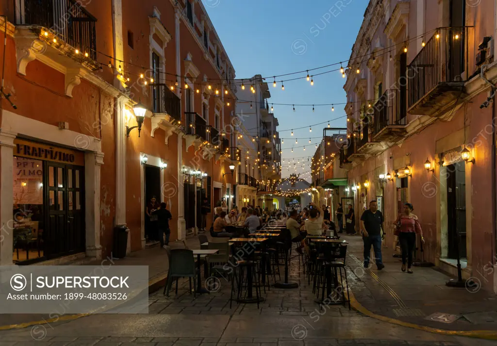 Restaurant tables in street at night with hanging lights, Campeche city, Campeche State, Mexico.