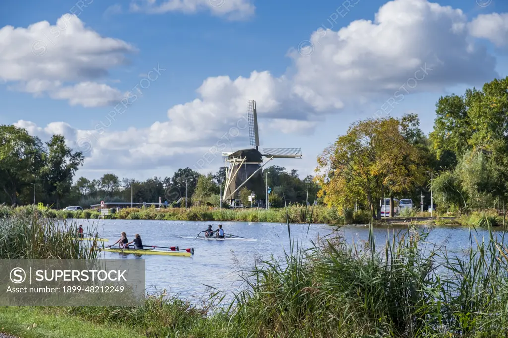 Crewing along the Amstel River with Rieker Windmill in background, Amsterdam, Netherlands.