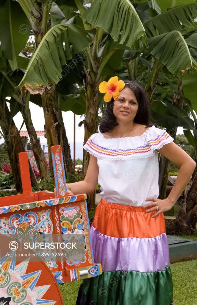 Costa Rican Woman In Traditional Dress Next To Traditional Carriage In And Around Costa Rica.