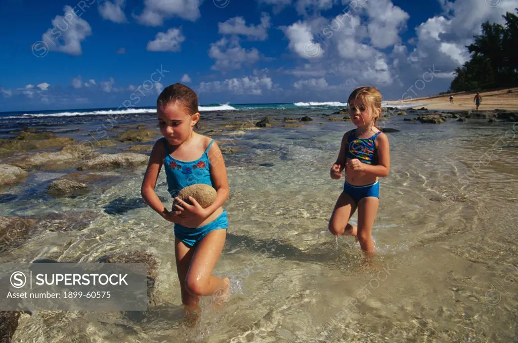 Two Girls (6 And 4) Playing With Rocks In A Tidal Pool On The North Shore Of Oahu, Hawaii.