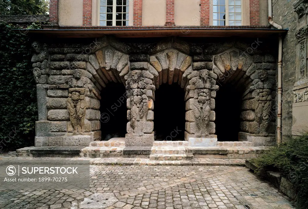 France, Fontainebleau, Palace of Fontainebleau. Detail. Caves 'grotte des Pins' with arcades, once used as prisons. The ancient prisons are made with stones ('concio') in rustic ashlar technique. Telamones figure define the pillars. Paving surface in the foreground.