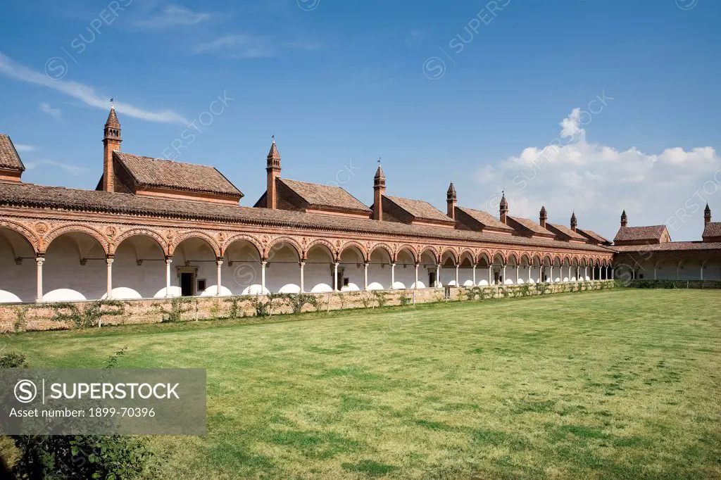 Italy, Lombardy, Pavia, Carthusian monastery. Detail. The grand cloister. The columns of the arcades present terracotta and white and pink marble decorations. On the pitched roofs of the buildings behind them are chimneypots. The windows of the monk cells, with the view on the loan, are also visible.