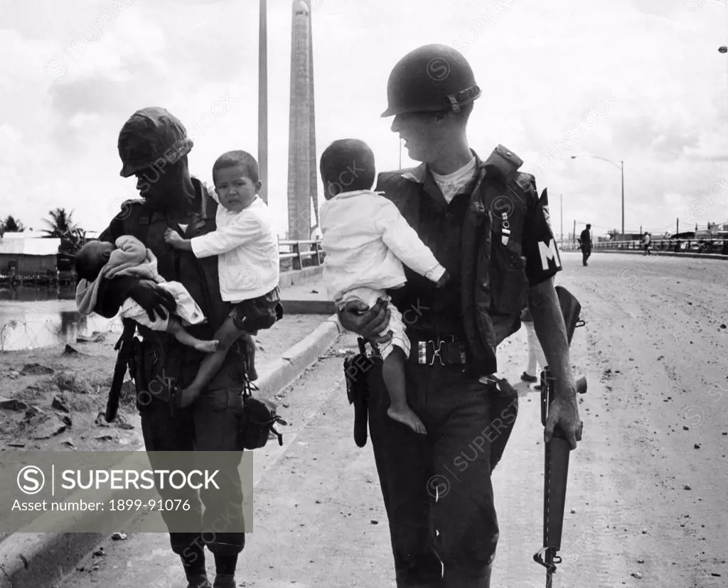 Two American soldiers are carrying a newborn and two children in their arms. War in Vietnam (1960-1975). Saigon (Vietnam), 1968.