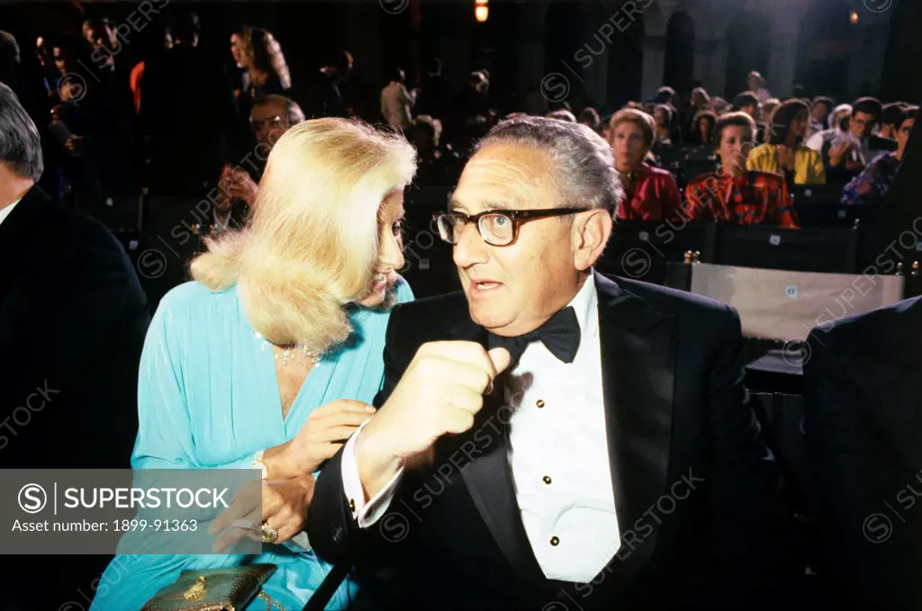 German-born American politician Henry Kissinger talking to a woman during a society party. 1990s